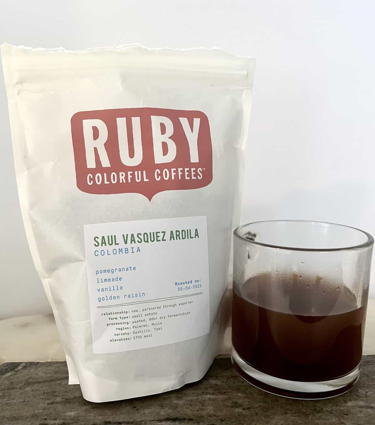 Ruby-Coffee-stands-next-to-a-cup-of-brewed-coffee-scaled